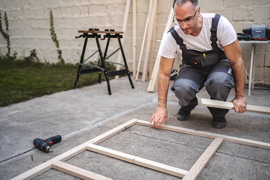 Un homme qui travaille pour fabriquer une porte de serre en bois