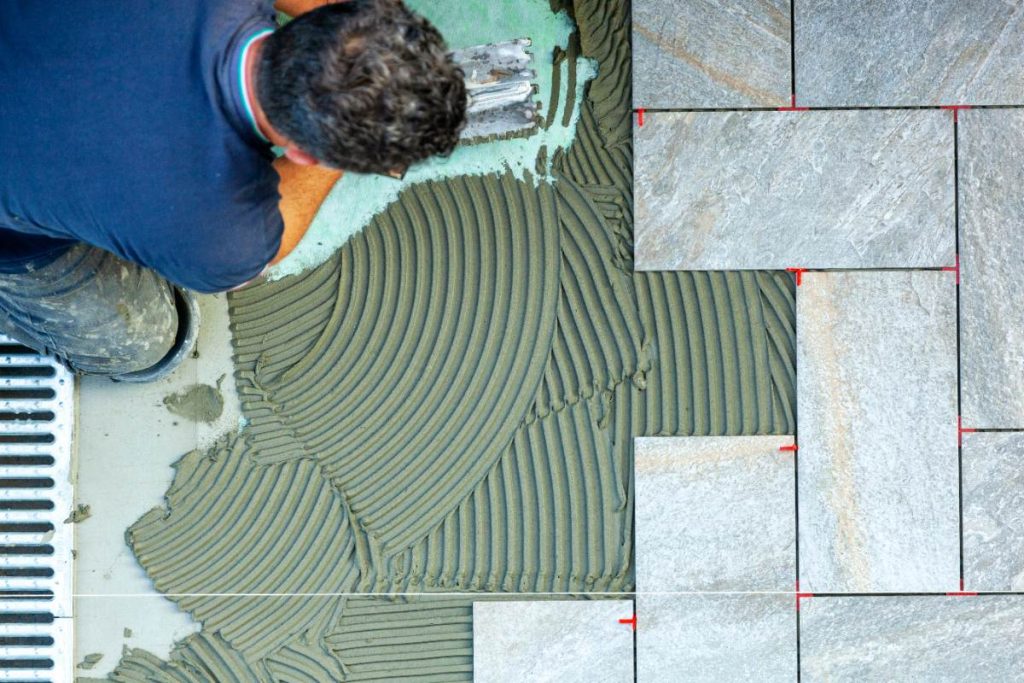 Personne étalant de la colle à carrelage avec une spatule crantée