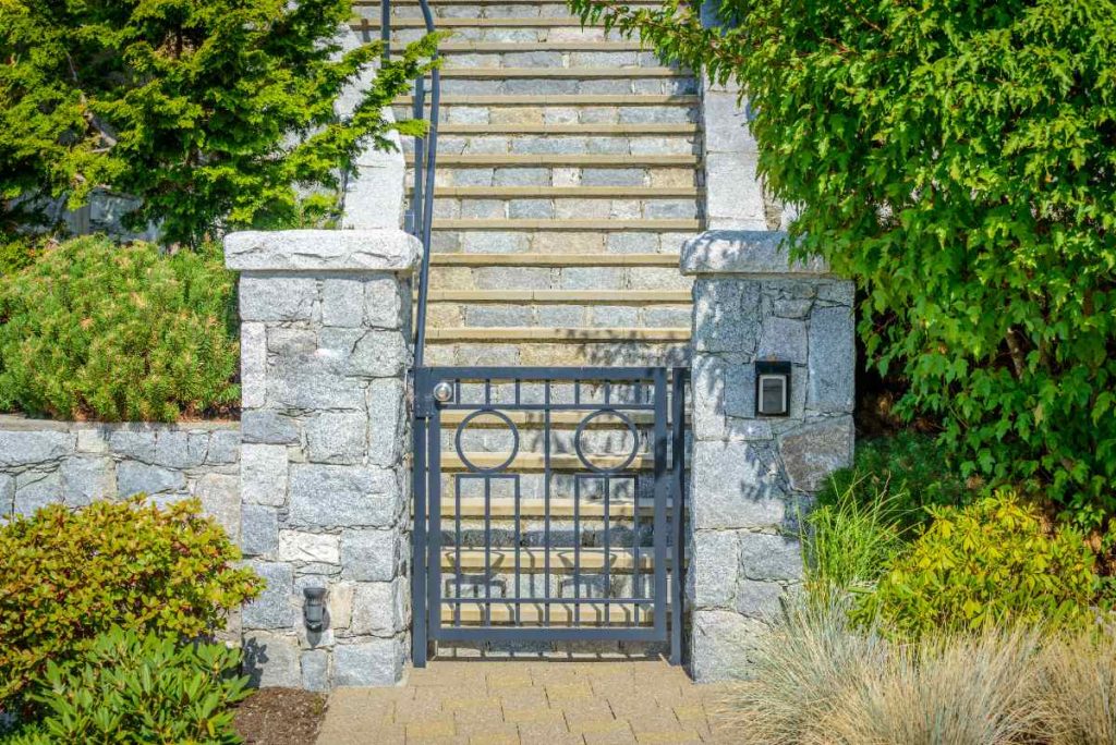 Un seuil de portail en pavés alignés, offrant une transition nette entre le jardin et l’allée