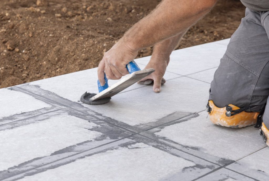 Un travailleur posant des carrelage à l'extérieur