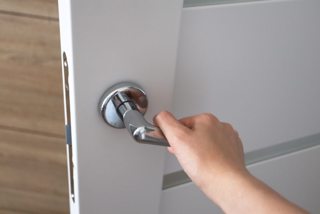 Main qui tient la poignée et ferme la porte