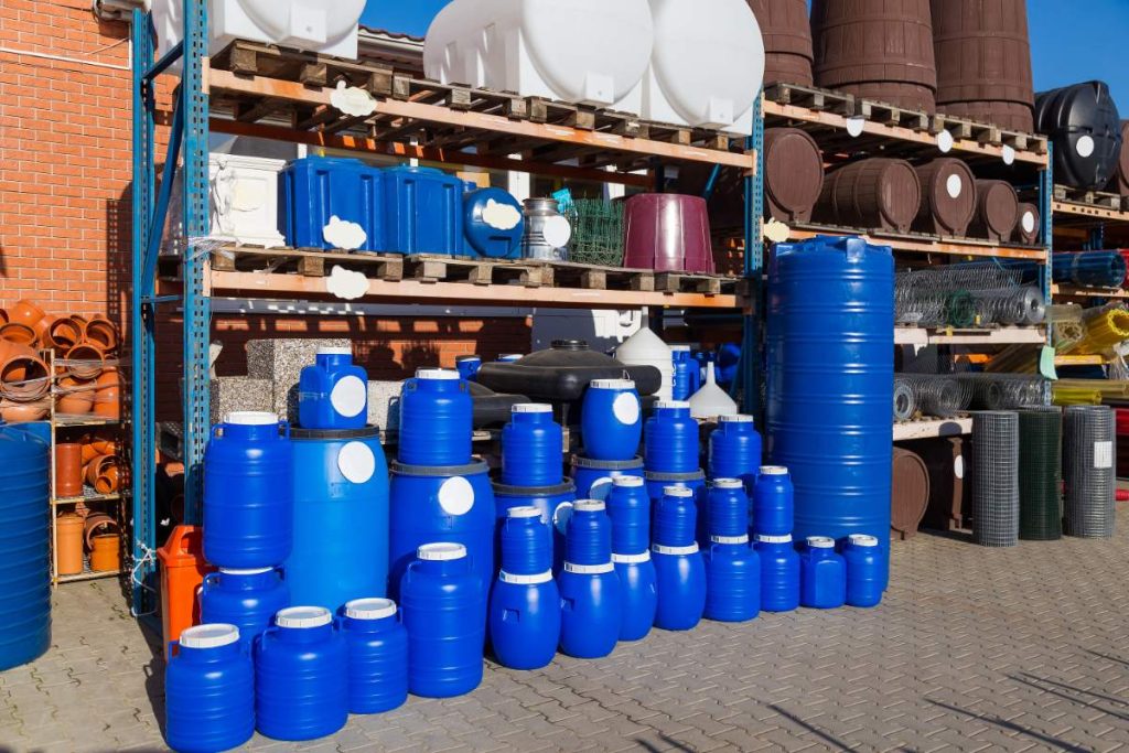 Des barils de stockage en plastiques rangés sur une étagère en bois