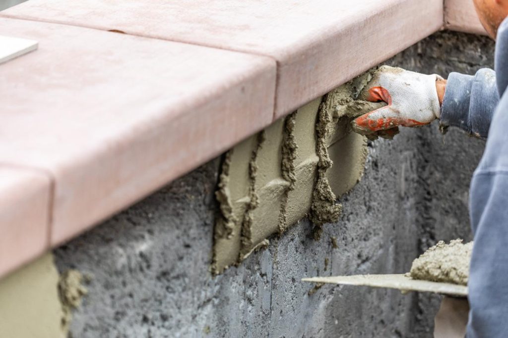 Un carreleur appliquant du ciment sur le mur avec une truelle