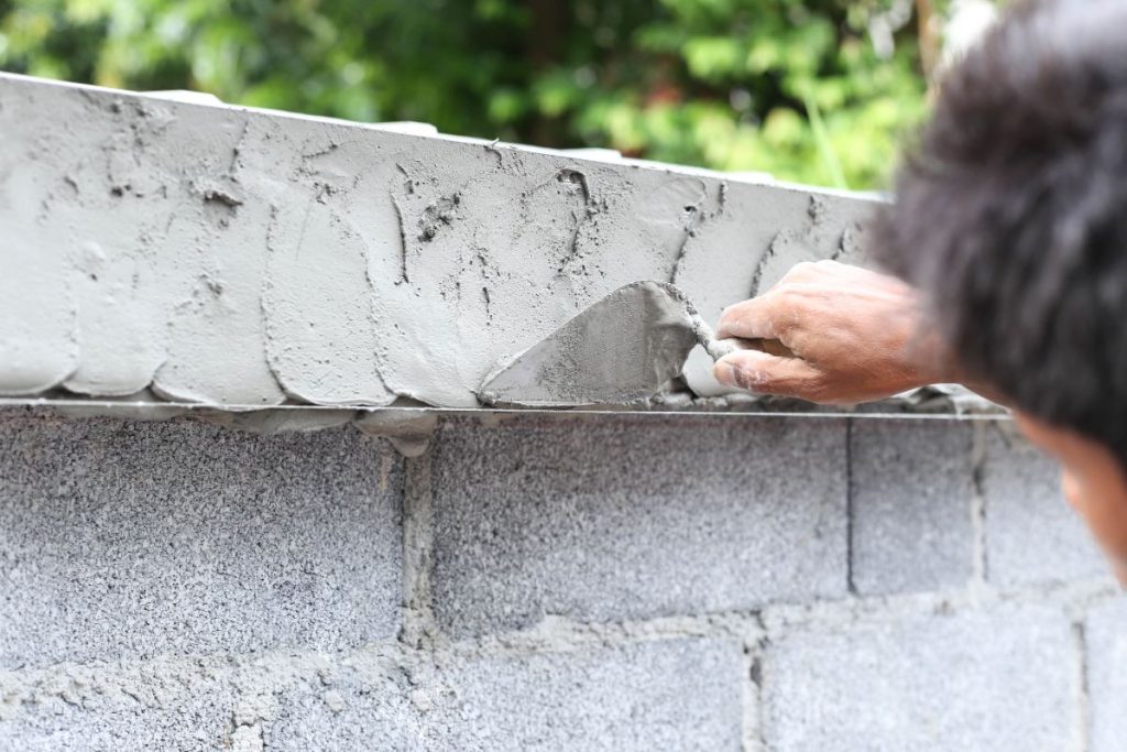 Un homme appliquant du ciment sur le mur