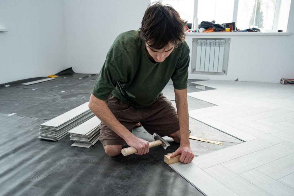 Peut-on installer du parquet flottant directement sur un ancien revêtement lino ? Un homme installant du nouveau parquet