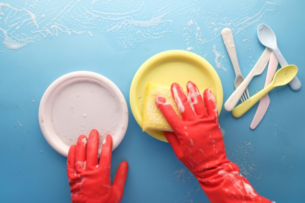 Une main gantée nettoyant des objets en plastiques