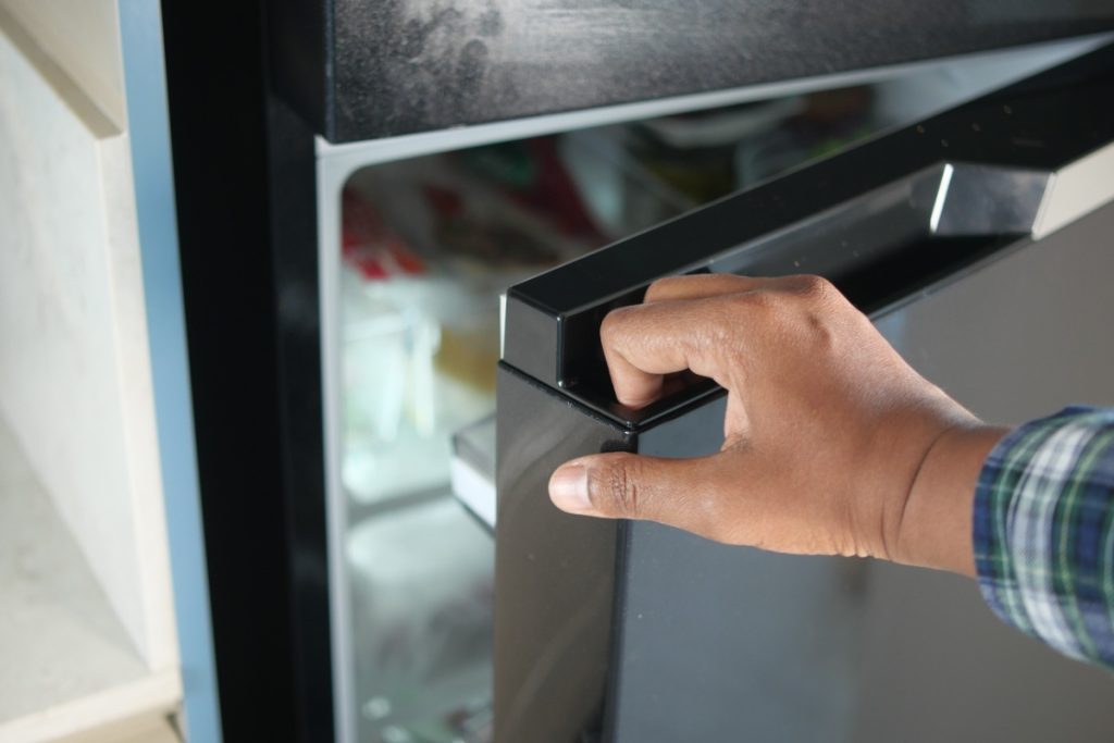 Pourquoi votre réfrigérateur s'arrête-t-il puis redémarre-t-il en permanence ? Une main ouvrant un frigo