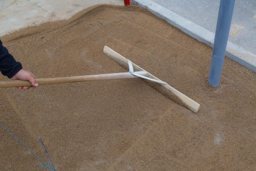 Un ouvrier lissant du sable avec un râteau