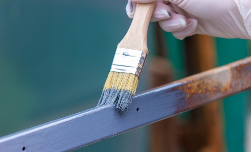 Une personne peigannt du poutre métallique