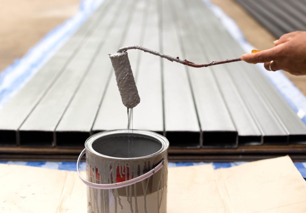 Une personne tenant un rouleau de peinture grise 