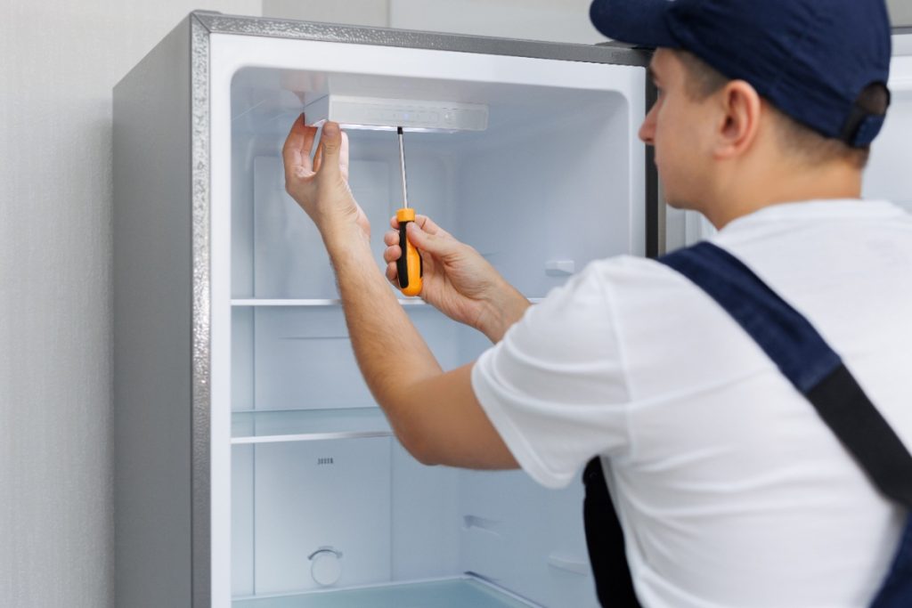 Pourquoi votre réfrigérateur s'arrête-t-il puis redémarre-t-il en permanence ? Un technicien qui répare un frigo