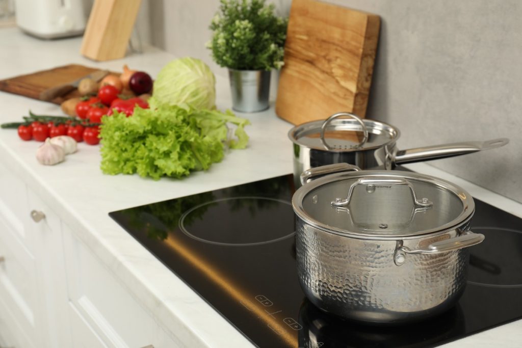 Un casserole posé sur la plaque induction avec des légumes 