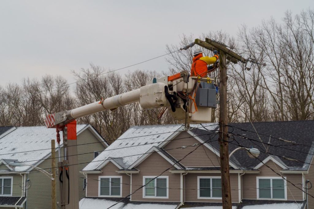 Un électricien qui installe des lignes électriques devant les maisons