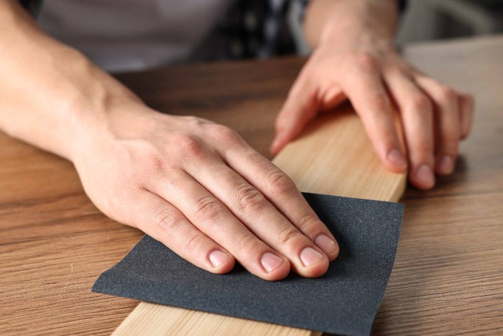 Une personne qui utilise du papier abrasif pour poncer une plancher