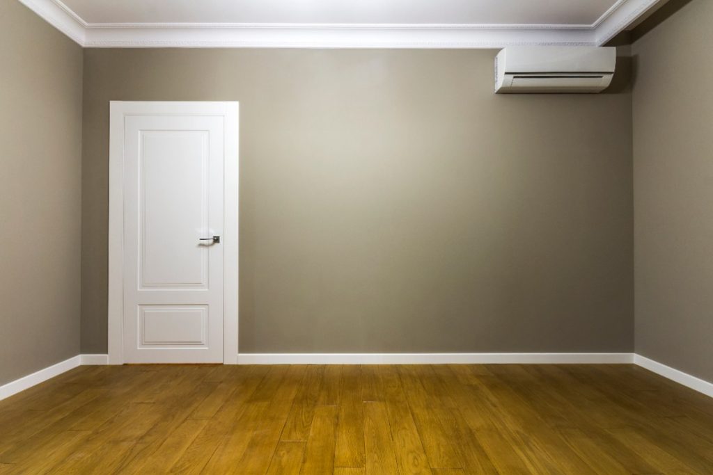 Une pièce vide avec une porte blanche et un climatiseur