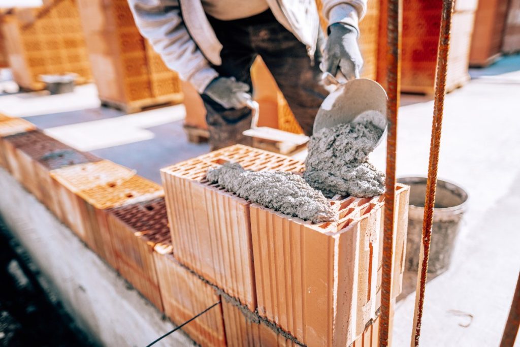 Un homme utilisant du mâchefer pour la construction du mur