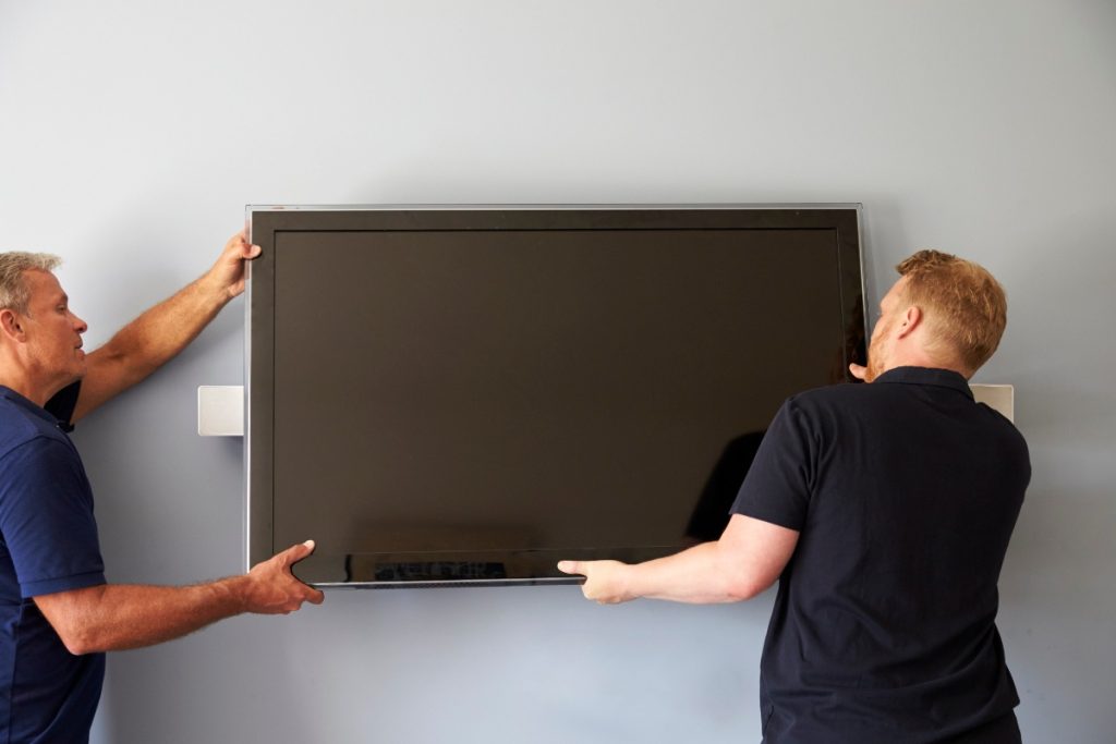 Des hommes accrochant une TV sur le mur