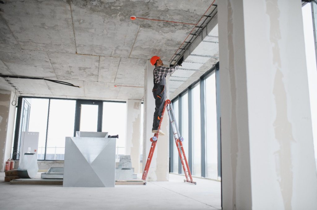 Un ouvrier de bâtiment installant un système de ventilation dans une maison