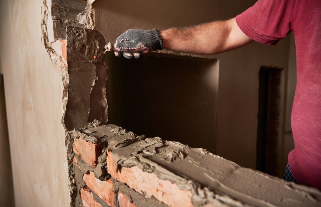 Un ouvrier portant un gant et enduisant le mur
