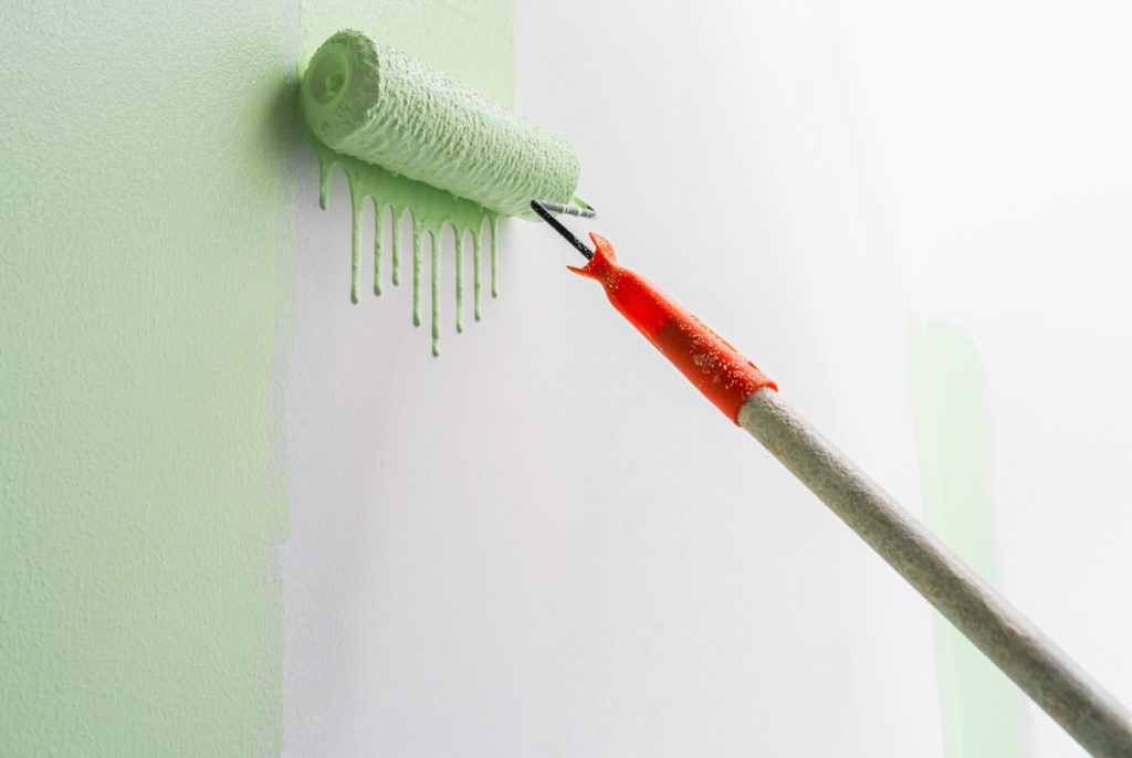 Un rouleau de peinture appliquant de la peinture verte sur le mur